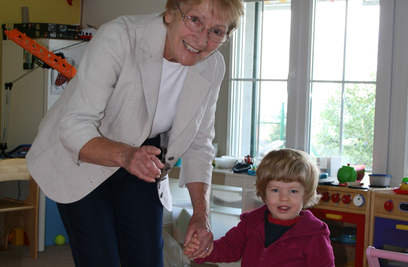 Lady wearing white jacket holding a child's hand