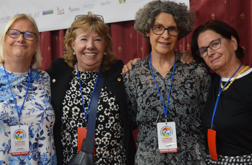 four women in aline in front of a red curtain backdrop