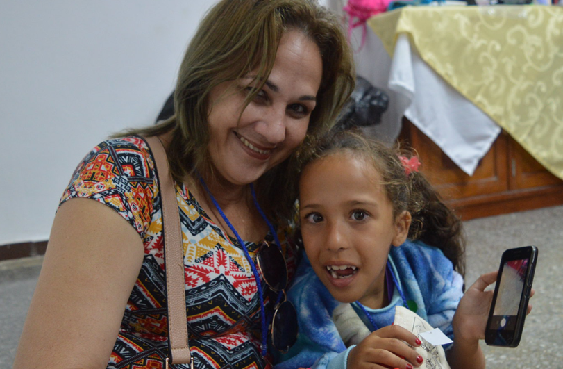 Woman in colourful top with child holding a mobile phone