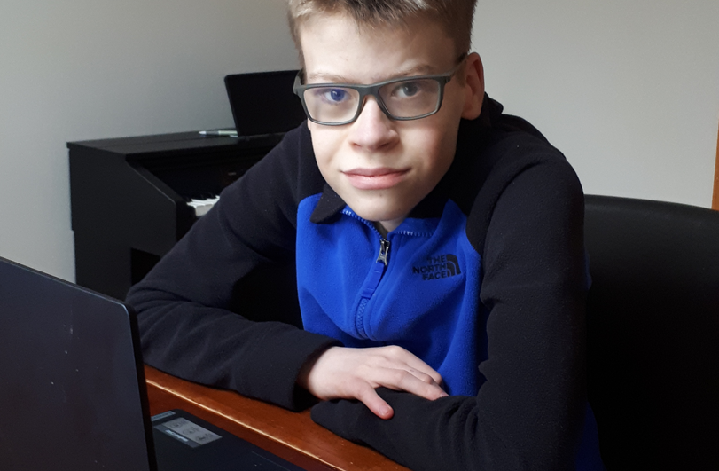 boy in a blue and black top sat at a laptop