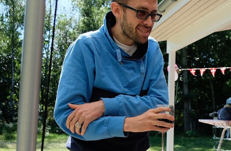 man in blue jumper outside a caravan holding a glass of wine