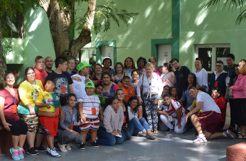 large group of people infront of green wall under trees