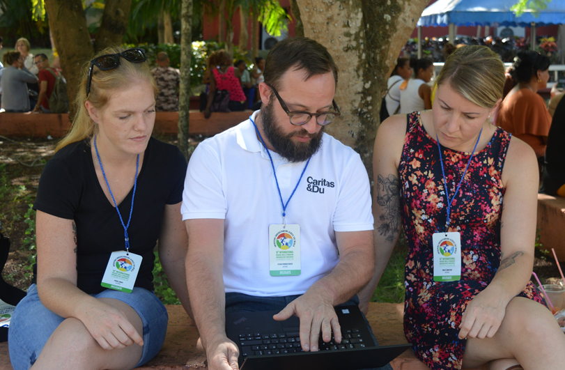 three people looking at a laptop outside