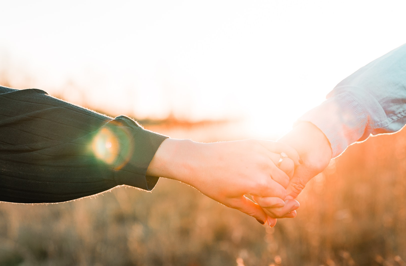 holding hands with sunset behind